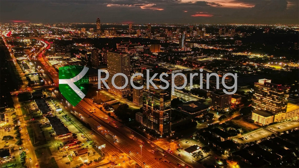 Sunrise aerial over Houston with the Rockspring mark on the tower, from the investor film