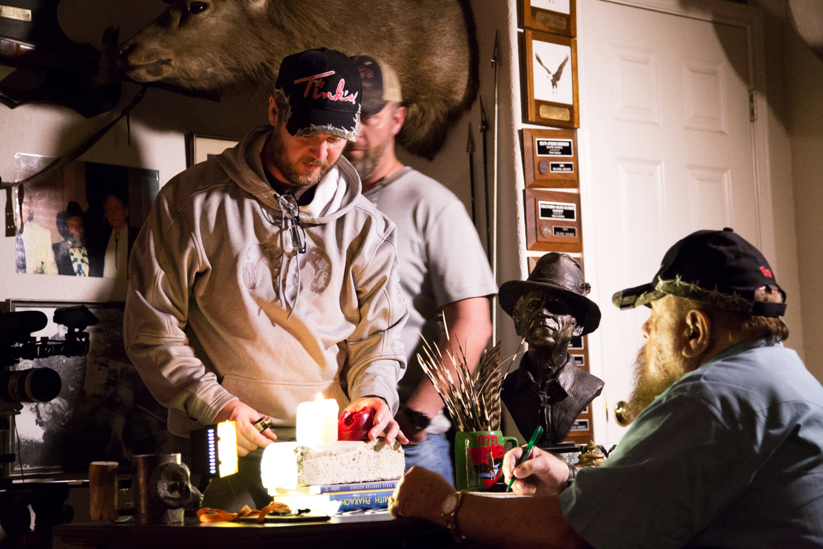 Sheldon Charron directing Tink Nathan at his desk, with a candle and a bust in the frame